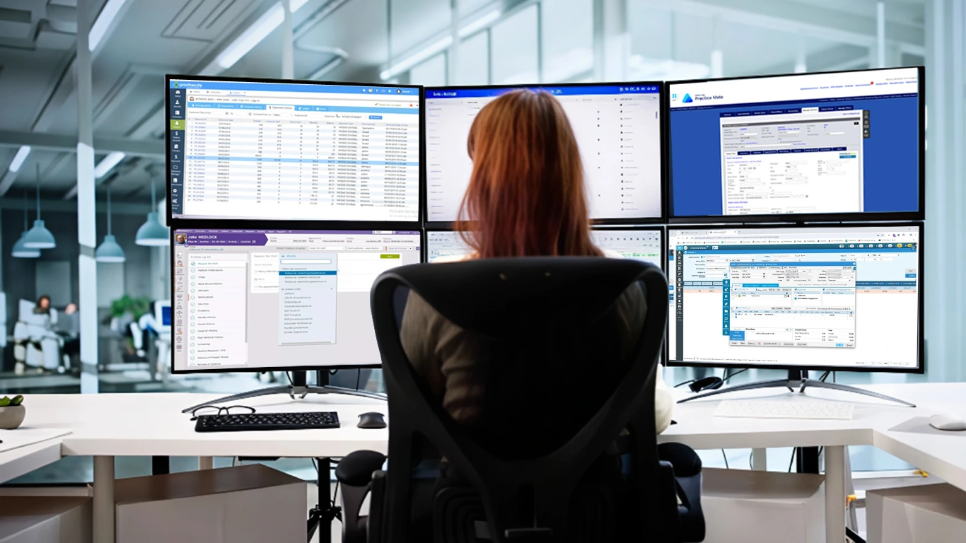 Billing specialist reviewing claims across multiple monitors